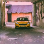 yellow car parked beside white wall